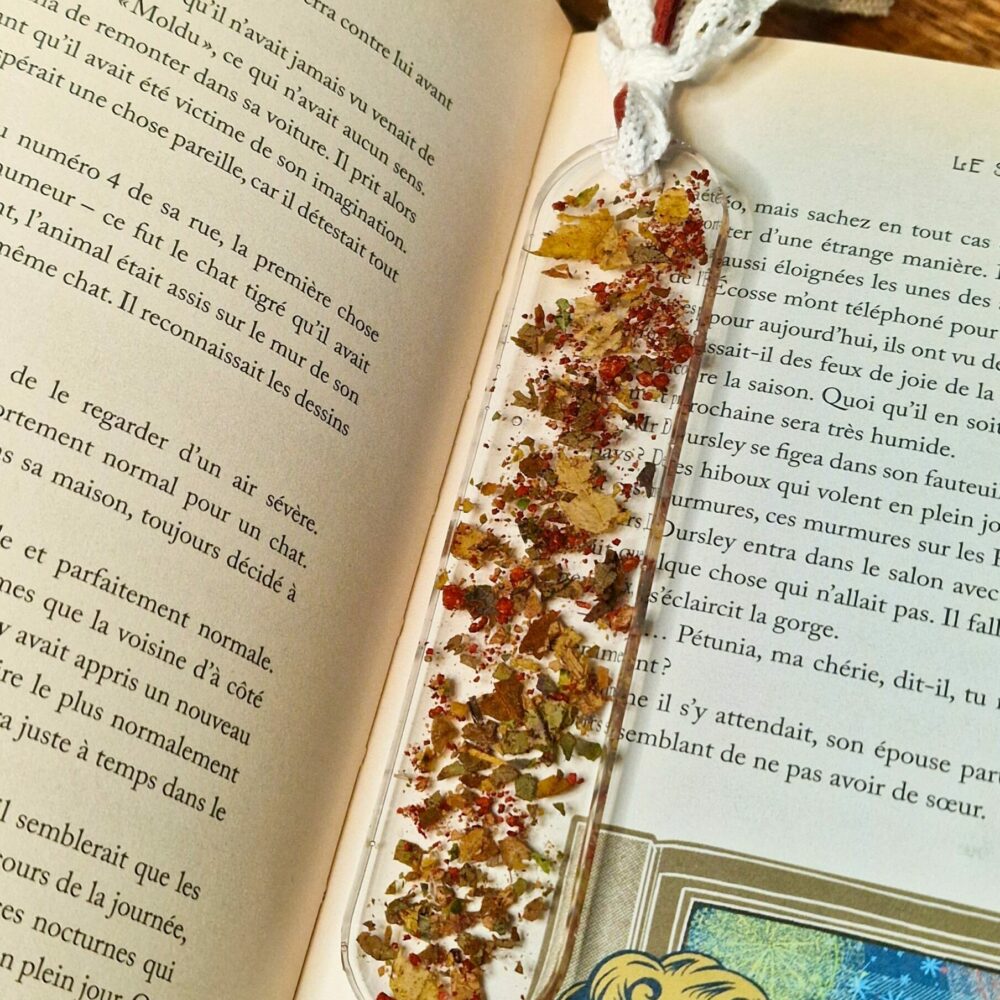 Marque-page artisanal en résine avec liège et feuilles naturelles posé sur un livre ouvert